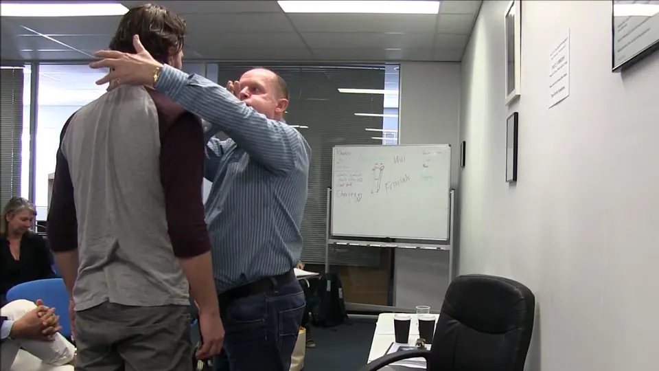 Rick Collingwood with a hand behind a standing student's head during a class demonstration