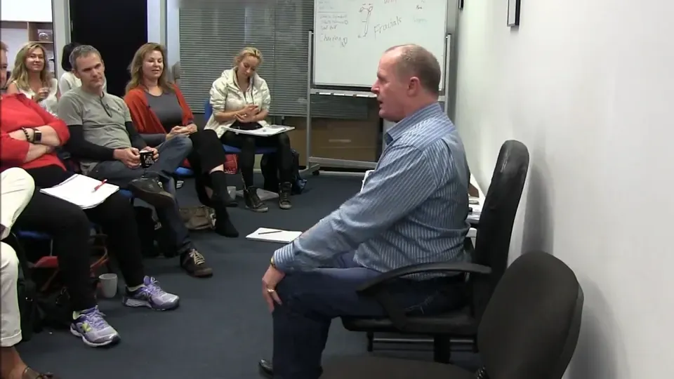 Rick Collingwood seated at the front of the room, teaching a class of diploma students