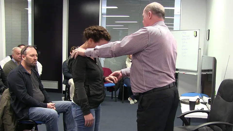 Rick Collingwood standing with his hands on a standing woman's shoulders, in front of seated students