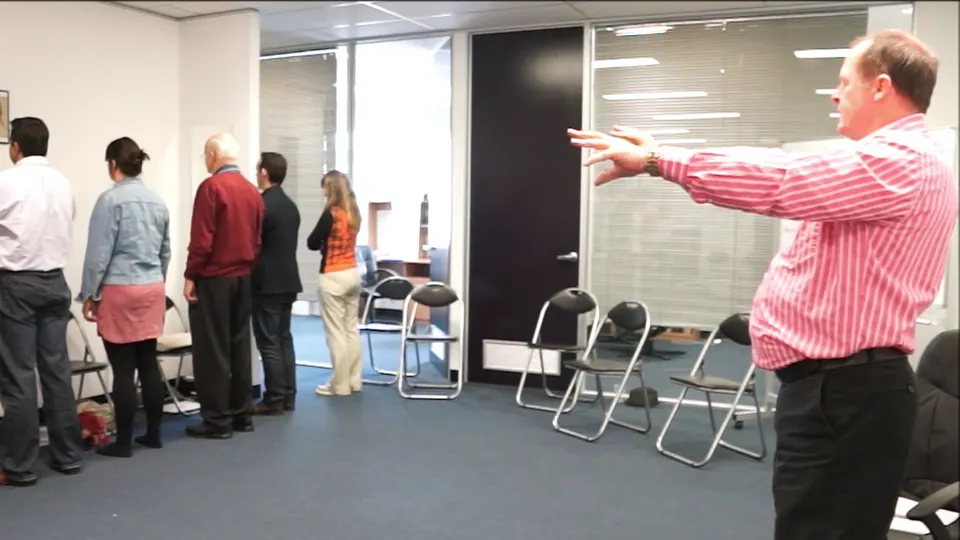Rick Collingwood extending his arms towards a line of standing students in a magnetic pull exercise