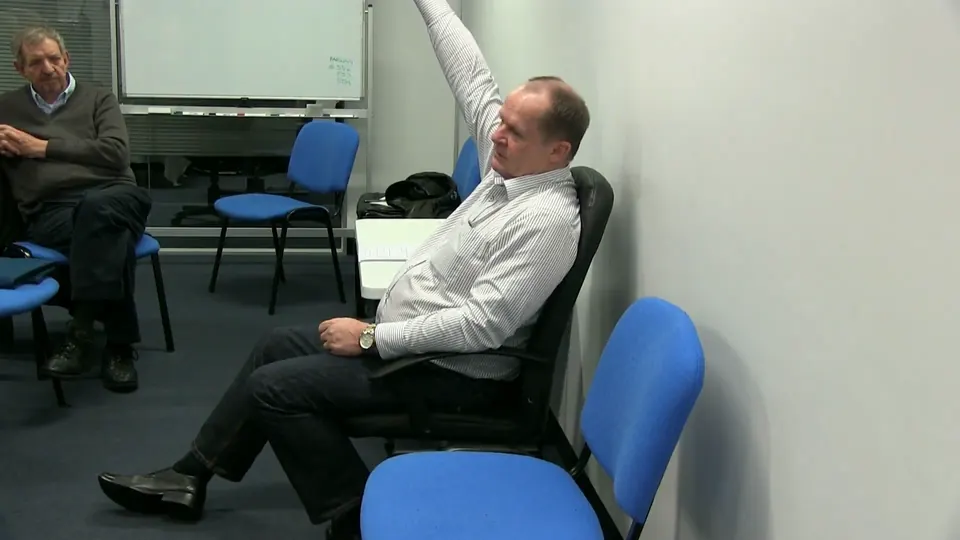 Rick Collingwood seated with one arm raised, demonstrating a point to a student