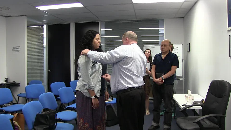 Rick Collingwood with a hand on a standing student's shoulder while other students look on