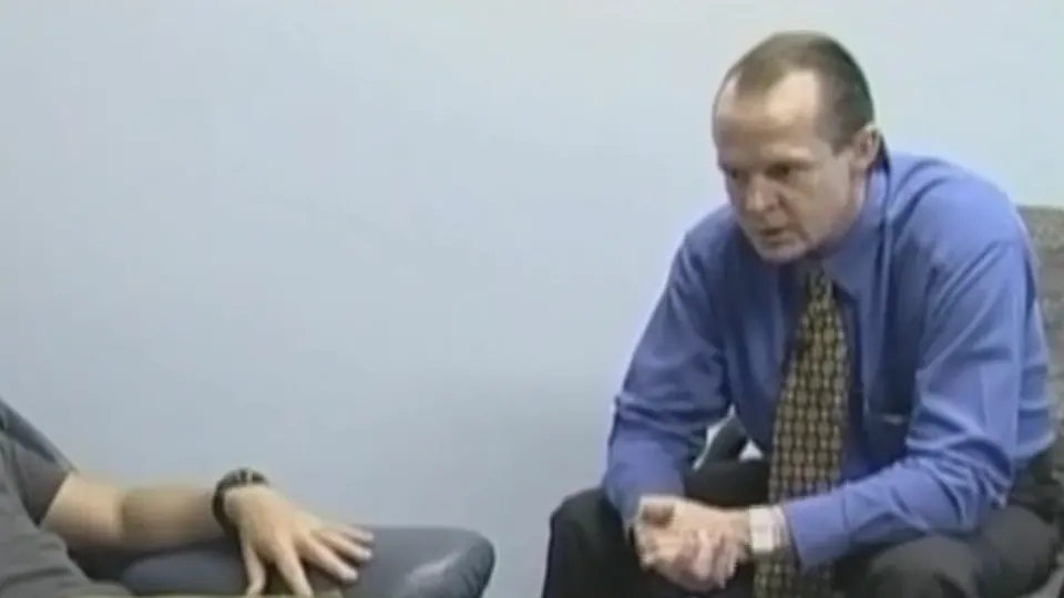 The hypnotherapist leaning forward in a chair, speaking during a recorded clinical hypnotherapy session