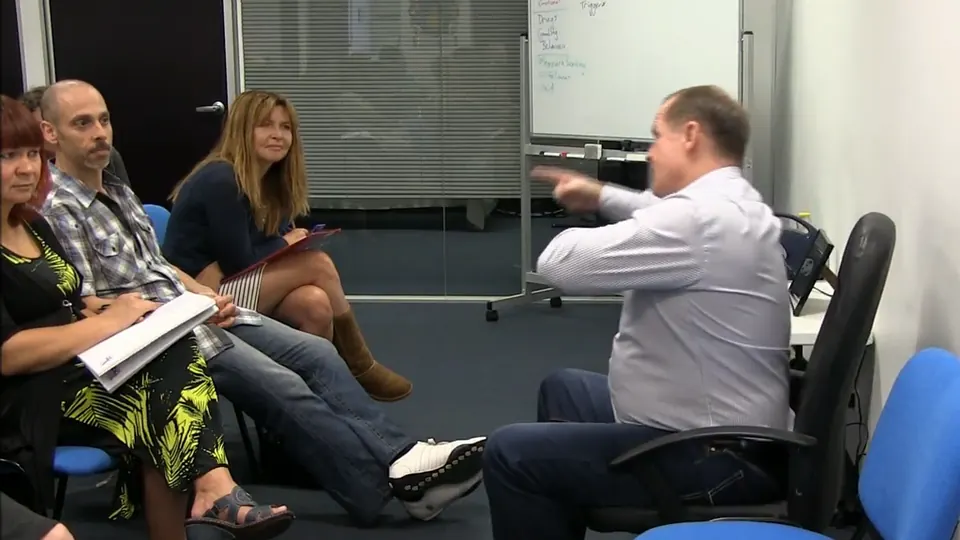 Rick Collingwood pointing as he talks to three students seated opposite him
