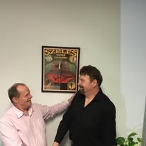 Rick Collingwood with James Szeles, beside a framed Szeles poster.